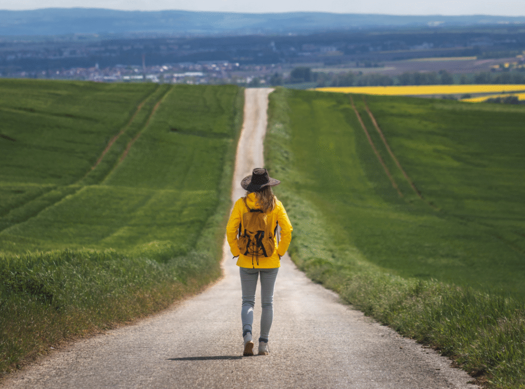 Midlife woman walking a winding path outdoors, symbolizing the menopause journey and personal growth during perimenopause and postmenopause.